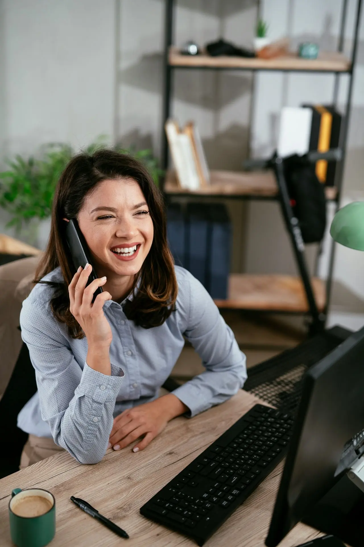 Businesswoman smiling while on the phone in front of computer